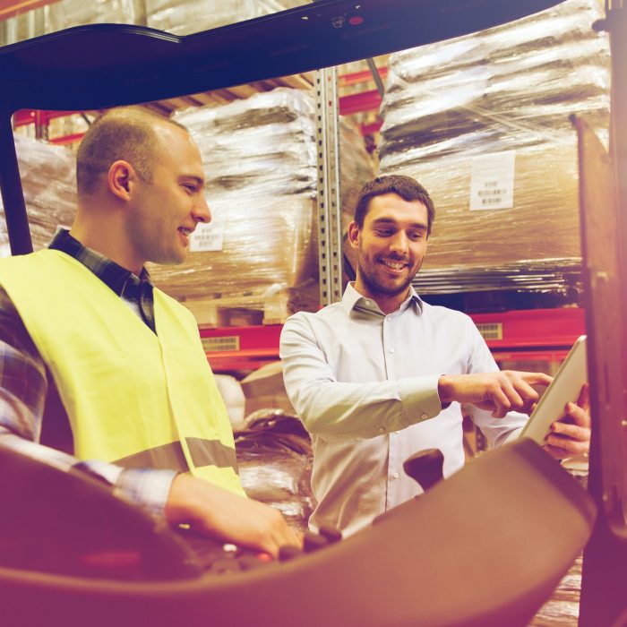 happy men with tablet pc and forklift at warehouse